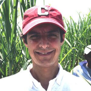 Henry Green ’95, MEng ’96 in a Guatemalan sugarcane field wearing a Cornell cap