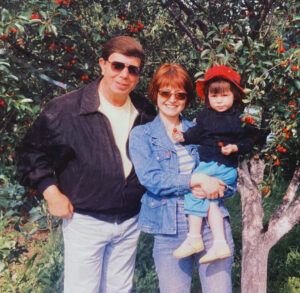 (L to R) Maryna’s father Vadim, her mother Svitlana, and Maryna under the cherry tree in her grandparents’ garden in June 2000