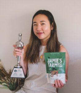 Jamie holds a trophy in one hand and a bag of Jamie's Farm granola in the other