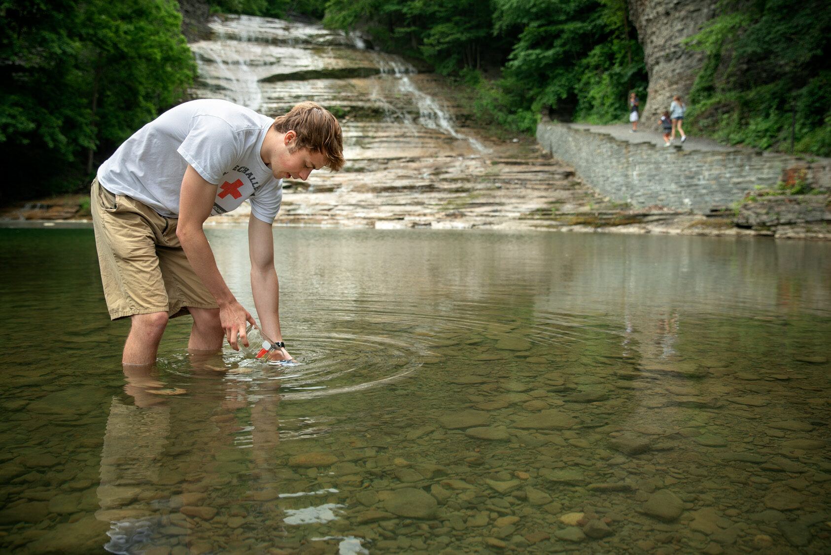 A Cornell undergraduate collects a water sample at Buttermilk Falls State Park