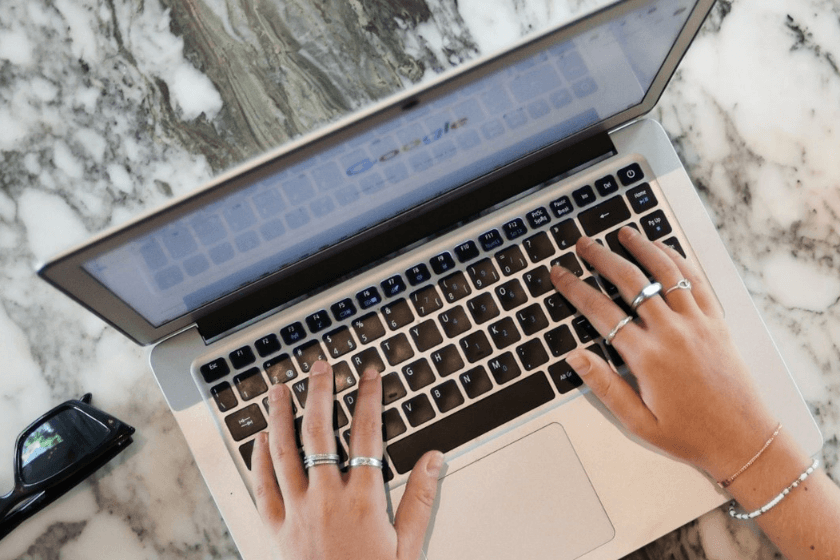 person's hands typing on a laptop