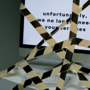 A desktop screen with text "unfortunately, we no longer need your services" that has been taped over with caution tape