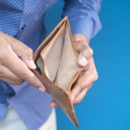 Close up of a person wearing a blue shirt holding open an empty, tan wallet