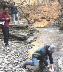 Doctoral students in Nicole Fernandez’s research group collect a water sample from Cascadilla Creek. From back to front: Kayla Russo, Jiawei Wang, and Hunter Jamison