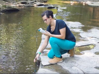 Nicole Fernandez, assistant professor of Earth and Atmospheric Sciences, takes a pH measurement in Cascadilla Creek near the Cornell Faculty Tennis Club.