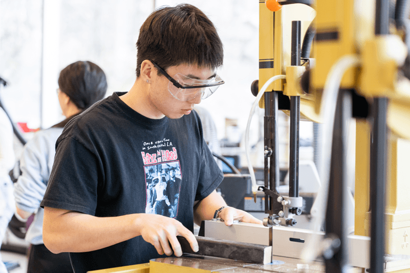 A student using a drill in a design laboratory