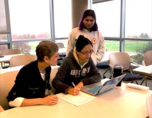 Kari Smoker with Ithaca College VITA program tax interns and masters of accounting students Yiang Jiang (seated) and Matt Naveran (standing). Matt will help oversee interns and review returns for the international community during the 2024 tax season.