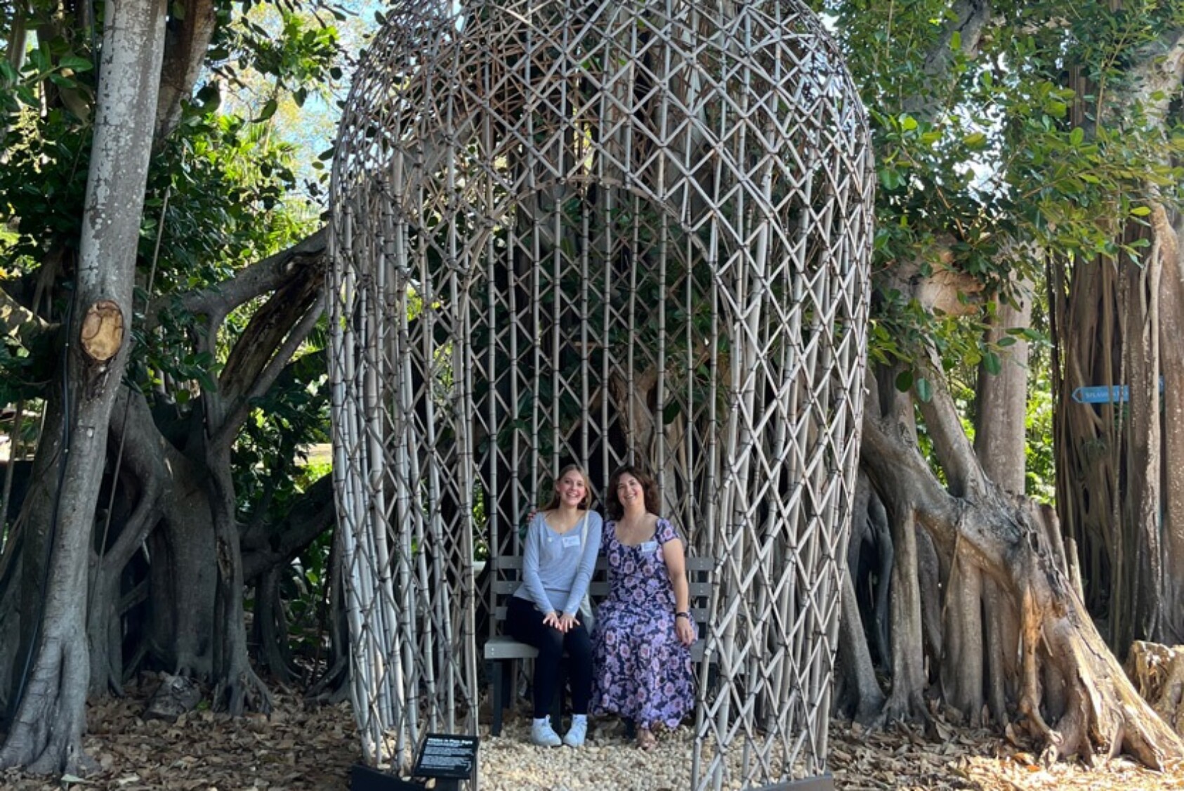 Karon Coleman ’88 sits next to her daughter Cecilia inside “Hidden in Plain Sight,” a 25-foot-tall Eastern screech owl. This sculpture acknowledges that this artwork and Pinecrest Gardens are located on the unceded ancestral homelands of Florida Native peoples.
