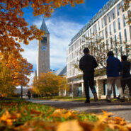 Students walk past Olin Library in fall, with McGraw Tower in the background.