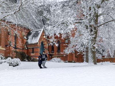 Students pass Sage Chapel in the snow.