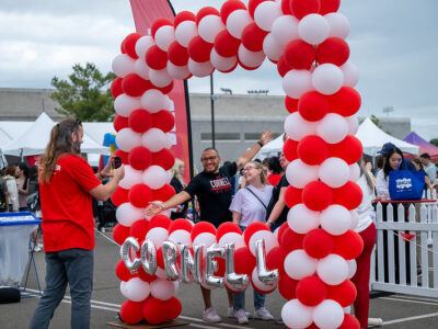 Homecoming 2024 attendees post in a Cornell-themed balloon arch at the Fan Festival