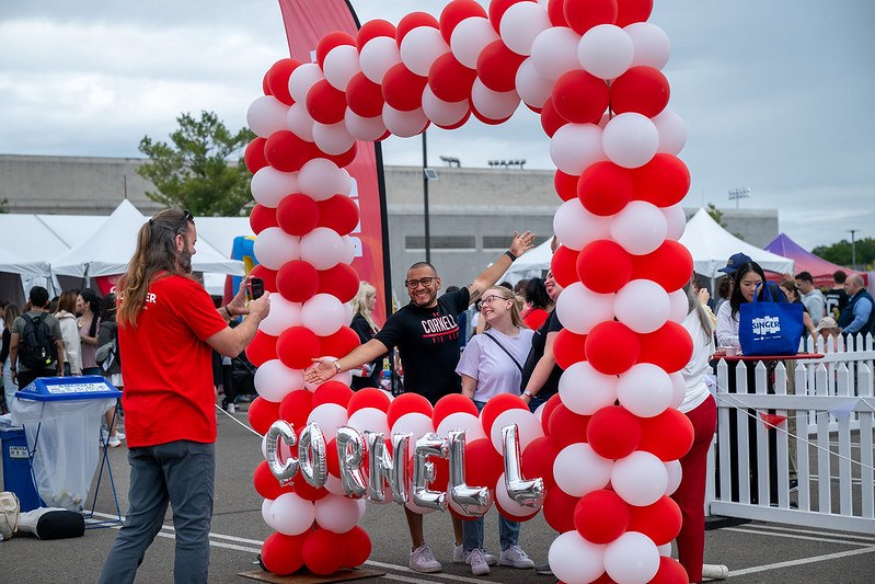 Homecoming 2024 attendees post in a Cornell-themed balloon arch at the Fan Festival