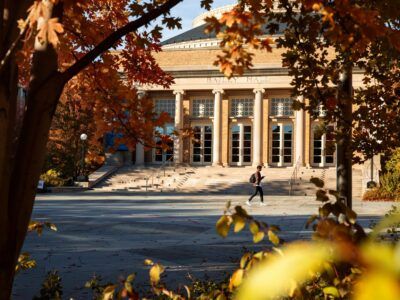 A student traverses Bailey Plaza amid fall foliage.