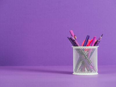 pen holder with various pens and pencils on purple surface