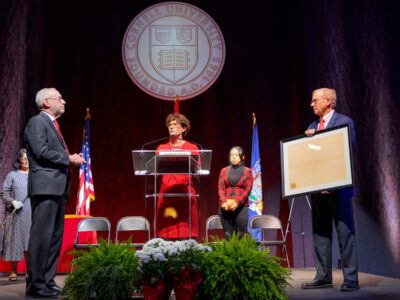Board of Trustees Chair Anne Meinig Smalling ’87 (center) presides over the inauguration of Mike Kotlikoff (left) as Life Trustee Ezra Cornell ’70, BA ’71, displays the University Charter. In the background are faculty-elected trustee Durba Ghosh (far left), holding the mace, and employee-elected trustee Hei Hei Depew, MBA ’25, who presented the seal.