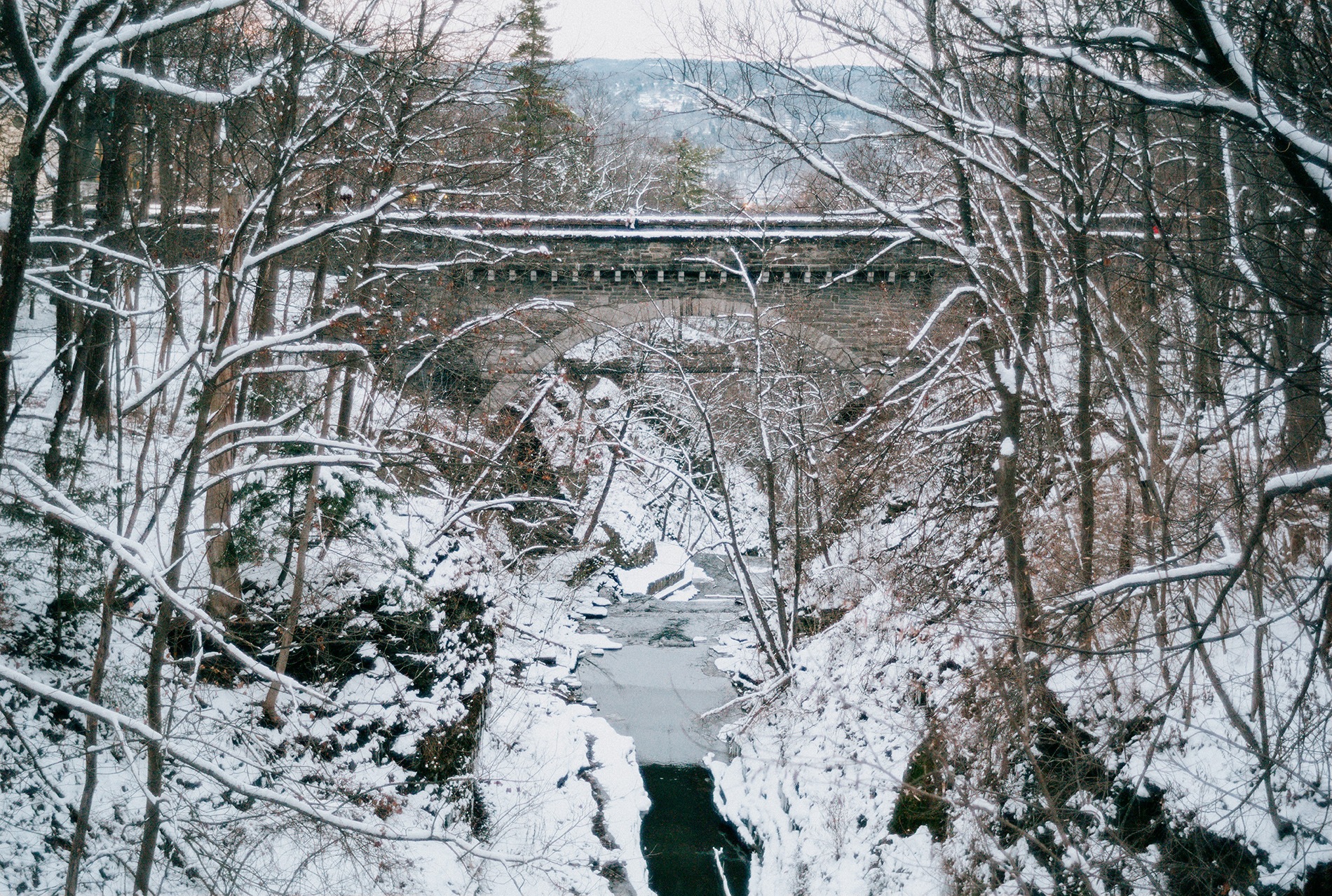 Cascadilla Creek sweeps silently under an empty College Ave. bridge.