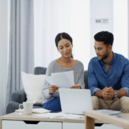 Young couple sitting on couch and looking at documents