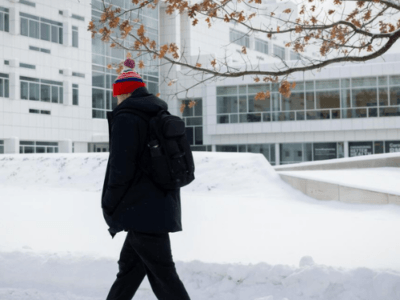 Cornellian walking in the snow outside Weill Hall