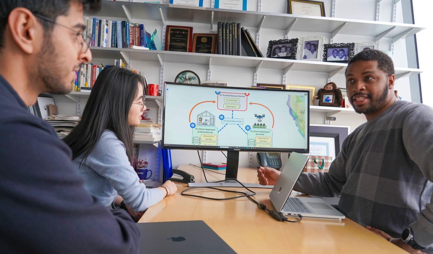 Clockwise from left: PhD students Salman Abid and Shuangyu Lei speak with Computer Science Prof. Hakim Weatherspoon about the data platform they are creating for CAST. Photo by Jackie Swift.
