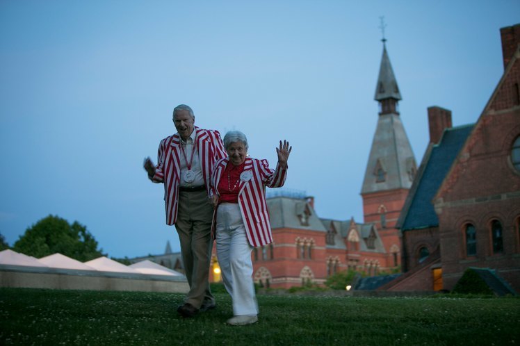 Two older alums wearing red striped blazers